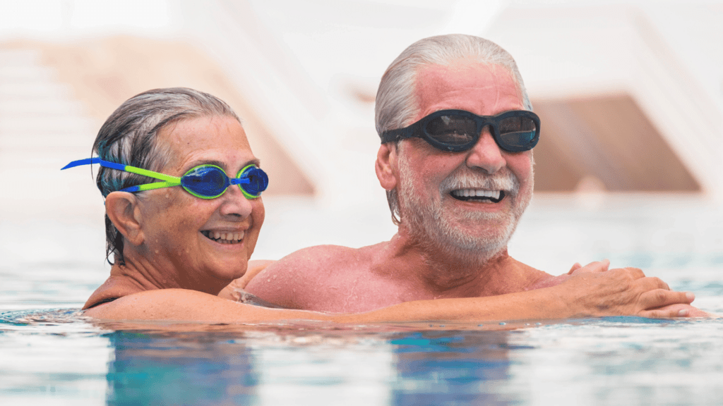 Older couple having fun swimming and smiling.